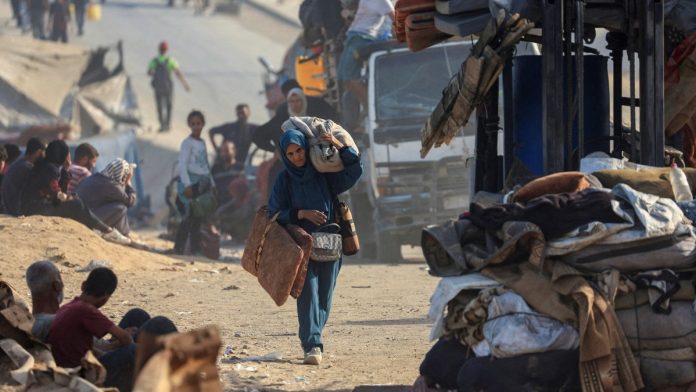 இஸ்ரேலிய இராணுவ நடவடிக்கை காரணமாக வடக்கு காசாவிலிருந்து தப்பி ஓடிய ஒரு பாலஸ்தீனியப் பெண், செப்டம்பர் 22, 2025 அன்று இஸ்ரேலியப் படைகள் காசா நகரவாசிகளை தெற்கே வெளியேற உத்தரவிட்டதைத் தொடர்ந்து, தனது உடைமைகளுடன் தெற்கு நோக்கி நடந்து செல்கிறார். | தாவூத் அபு அல்காஸ் | ராய்ட்டர்ஸ்