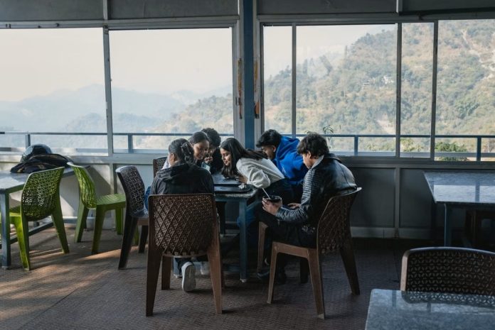 டேராடூனில் சாலையோர உணவகம் ஒன்றில் மாணவர்கள் குழு ஒன்று ஜியோஹாட்ஸ்டாரில் நிகழ்ச்சிகளைப் பார்க்கின்றனர். புகைப்படக் கலைஞர்: எல்கே ஷோலியர்ஸ்/ப்ளூம்பெர்க்